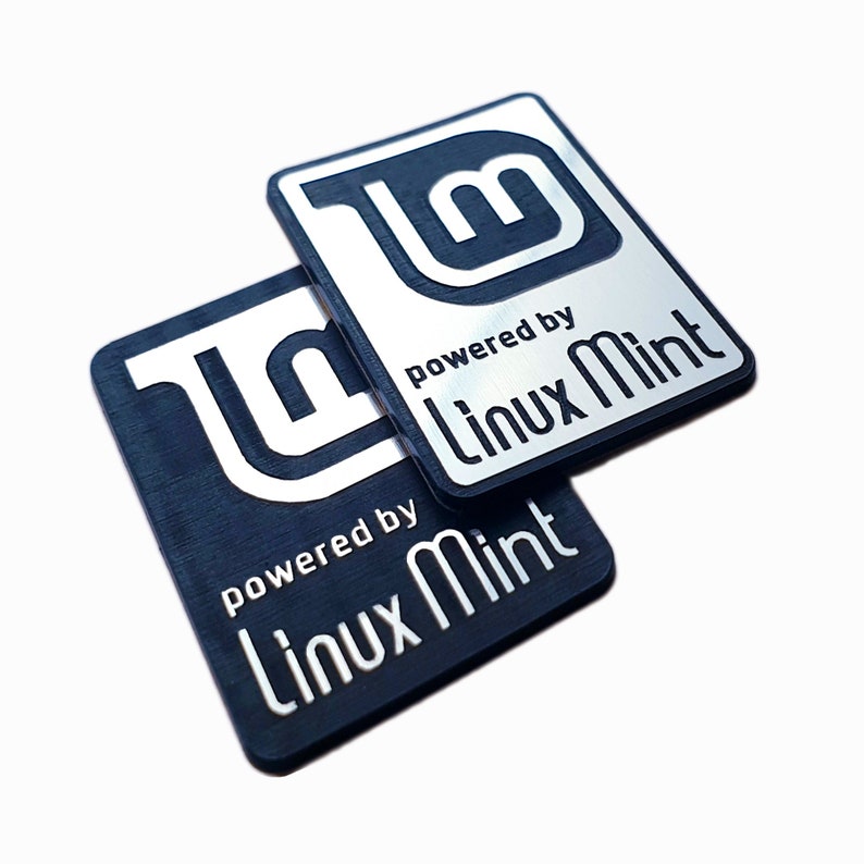 May include: Two black and silver stickers with the Linux Mint logo and the text "powered by Linux Mint".