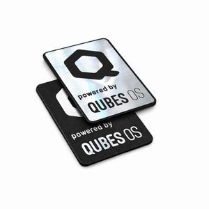 Puede incluir: Dos pegatinas rectangulares de metal. Una es plateada con un logotipo "Q" negro en forma de hexágono y el texto "powered by QUBES OS". La otra es negra con el mismo logotipo y texto.