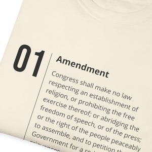 Könnte beinhalten: Ein weißes T-Shirt mit dem Text "01 Amendment" und dem ersten Zusatzartikel zur US-Verfassung.