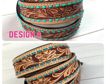 Op de afbeelding: Twee leren riemen met turquoise en bruine bloemenmotieven. De riemen zijn opgerold en de bovenste riem heeft de tekst "DESIGN A" en de onderste riem heeft de tekst "DESIGN B".