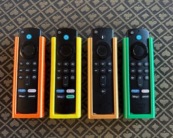 May include: Four different colored remote control holders for streaming devices. The holders are orange, yellow, orange, and green. The remotes are black and have buttons for Netflix, Hulu, Disney+, and Peacock.