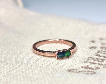 May include: A rose gold ring with a dark green rectangular gemstone.