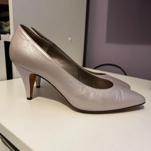 May include: A pair of silver leather pumps with a pointed toe and a stiletto heel.