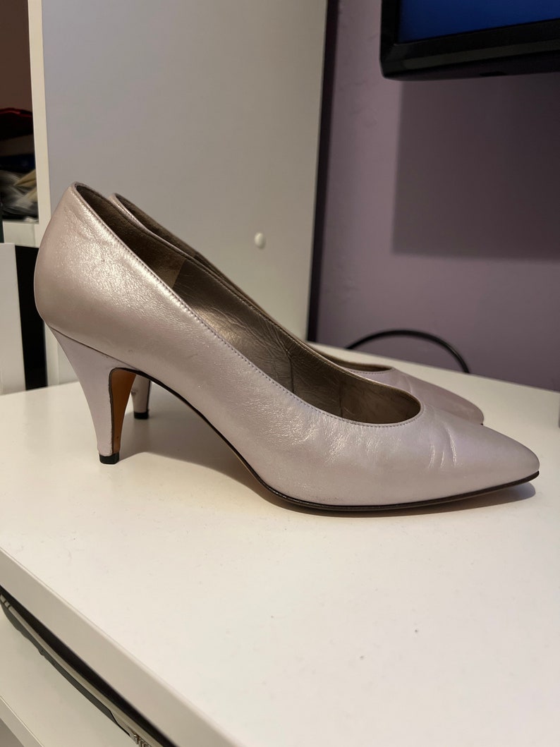 May include: A pair of silver leather pumps with a pointed toe and a stiletto heel.