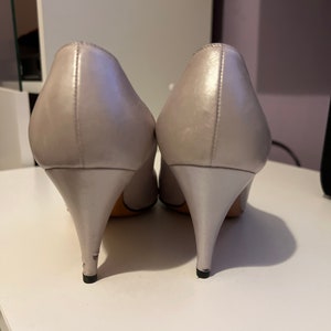 May include: A pair of silver high-heeled shoes with a pointed toe.