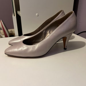 May include: A pair of silver leather pumps with a pointed toe and a stiletto heel.