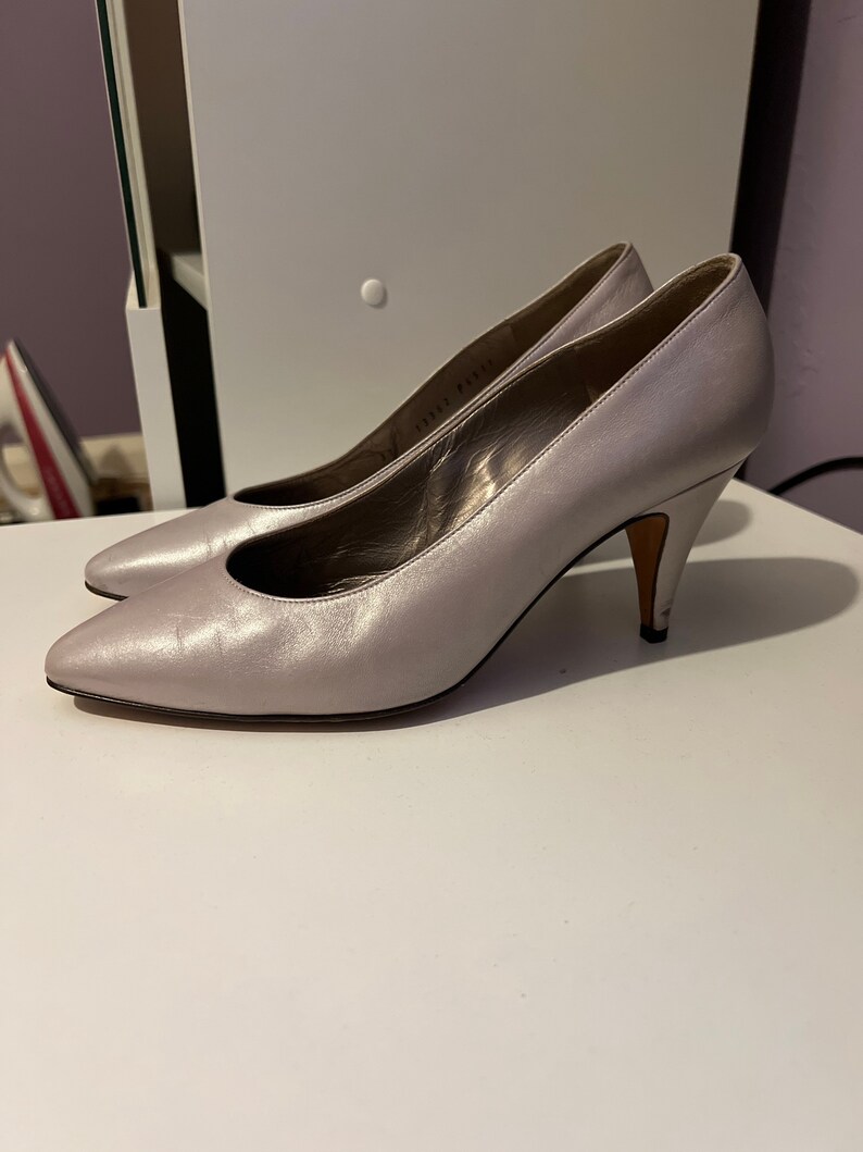May include: A pair of silver leather pumps with a pointed toe and a stiletto heel.