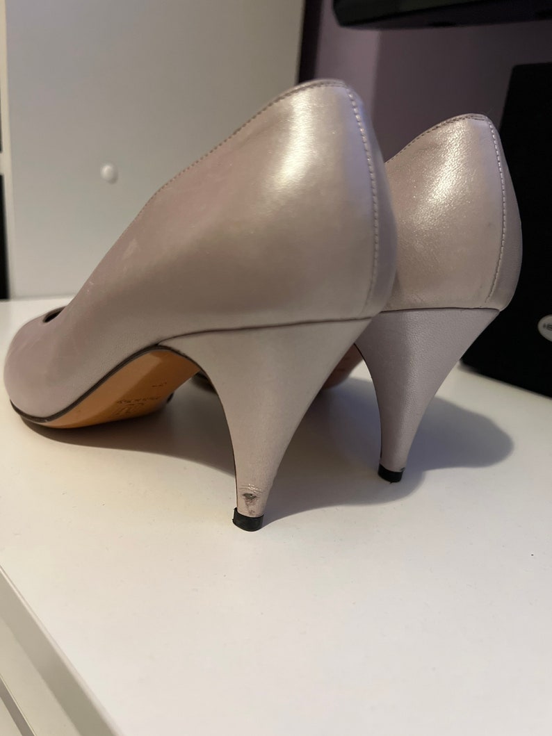 May include: A pair of light gray satin high heels with a pointed toe and a stiletto heel.