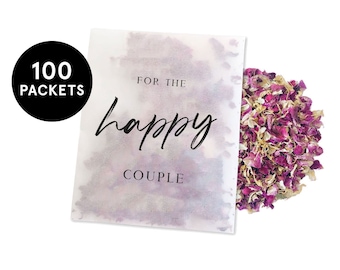 May include: A white paper bag with the text "For the happy couple" printed on it. The bag contains pink and white rose petals. The bag is labeled with "100 packets".