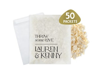 May include: A white paper bag with the text "THROW some LOVE LAUREN & KENNY" printed on it. The bag is filled with white flower petals and is labeled with a gold sticker that says "50 PACKETS".