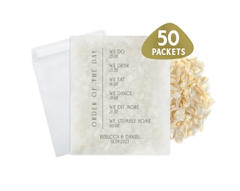 May include: A white envelope with a beige card inside. The card has a black and white text design that reads "Order of the Day" with a list of events and times. The text also includes the names "Rebecca & Daniel" and the date "01.09.2023". A pile of white confetti is in the upper right corner of the image. The text "50 Packets" is in a gold rectangle above the confetti.