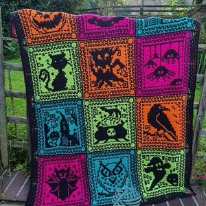 May include: A black crochet blanket with a colorful patchwork design featuring various Halloween-themed motifs, including a jack-o-lantern, a cat, a ghost, a spider, a cauldron, a raven, a bat, an owl, and a skeleton. The blanket is made with bright neon colors, including orange, green, pink, and blue.