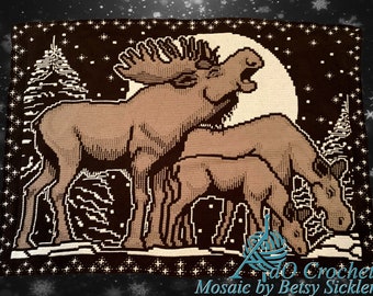 May include: A crochet pattern featuring a brown moose and a fawn standing in a snowy forest under a full moon. The pattern is called "Mosaic by Betsy Sickler".