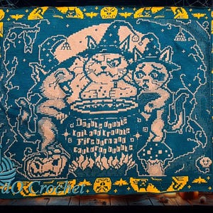 May include: A teal and yellow crocheted blanket with a Halloween theme. The blanket features two cats wearing witch hats, a cauldron, and the text "Double double toil and trouble, fire burn and cauldron bubble."