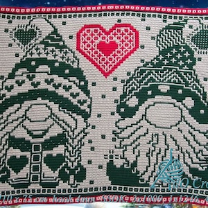 May include: Crocheted square featuring two gnomes with green hats and white beards, a red heart with white stitching, and a white background with a snowflake pattern. The text "Size 110 x 75 cm hook 4 mm" is at the bottom of the square.