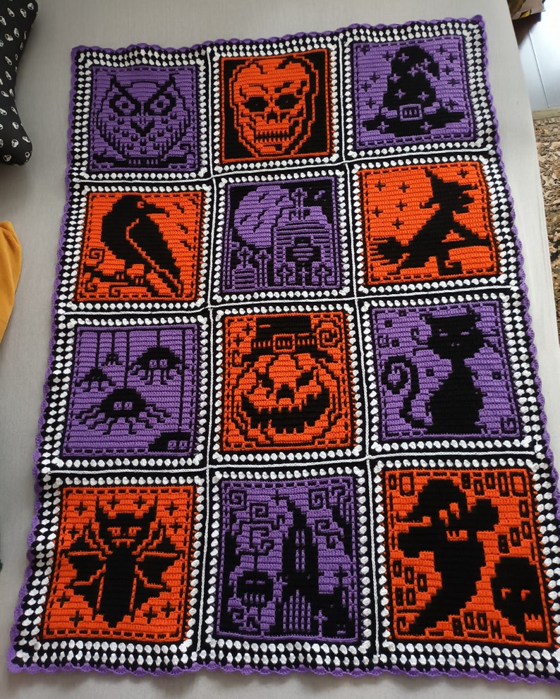 May include: A purple and orange crocheted blanket with a Halloween theme. The blanket is made up of nine squares, each featuring a different Halloween icon, including an owl, a skull, a witch's hat, a raven, a haunted house, a witch on a broomstick, spiders, a jack-o'-lantern, a black cat, a bat, a graveyard, and a ghost.