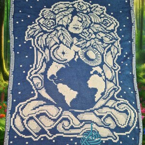 K&ouml;nnte beinhalten: Eine blaue H&auml;keldecke mit einem wei&szlig;en Design einer Frau mit einer Blumenkrone, die einen Globus h&auml;lt. Der Text "Mosaic by Alison Leathwood" befindet sich am unteren Rand der Decke.