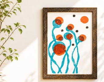 May include: Abstract art print in a dark wood frame. The artwork features a design of orange circles and blue, stem-like shapes on a white background. Small black dots are scattered around the orange circles. The print is displayed on a wooden surface.