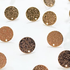 Könnte beinhalten: Ein weißer Teller mit 20 goldfarbenen Metallkreisen mit einem kleinen Loch in der Mitte. Die Kreise haben eine strukturierte Oberfläche.