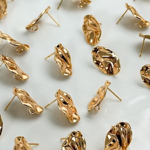 Könnte beinhalten: Eine Sammlung von goldfarbenen Ohrsteckern aus Metall mit einer unregelmäßigen, organischen und gewellten Oberflächenstruktur. Jeder Ohrstecker verfügt über eine kleine kreisförmige Öse an der Basis zum Befestigen von Schmuckteilen und einen geraden Stift.