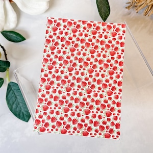May include: A white background with a repeating pattern of red strawberries.