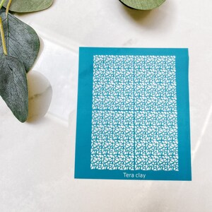 Op de afbeelding: Een blauwe sjabloon met een wit geometrisch patroon. De sjabloon is gelabeld "Tera clay".