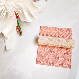 May include: A pink and white patterned rolling pin and a pink patterned silicone mat for baking and decorating cakes and cookies.