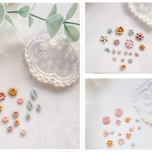 以下が含まれることがあります： ポリマークレイの花を作るためのシリコンモールドが3つあります。モールドは透明で、さまざまな花の形をしています。ピンク、イエロー、グリーンなど、さまざまな色の小さなポリマークレイの花もいくつかあります。