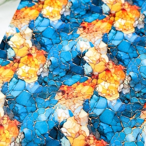 Puede incluir: Obra de arte abstracta con un patrón de mosaico. El diseño presenta una combinación de tonos azules, naranjas y amarillos, creando una apariencia vibrante y texturizada. La obra de arte tiene un efecto agrietado, similar a la piedra.