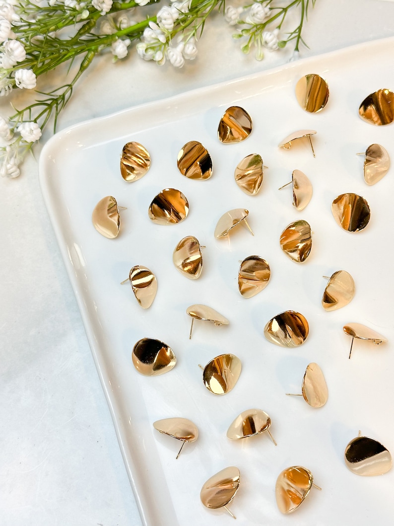 Peut inclure: Une collection de boucles d'oreilles rondes et ondul&eacute;es dor&eacute;es sur une assiette blanche. Les boucles d'oreilles sont toutes de la m&ecirc;me forme et de la m&ecirc;me taille, et elles sont dispos&eacute;es de mani&egrave;re al&eacute;atoire.