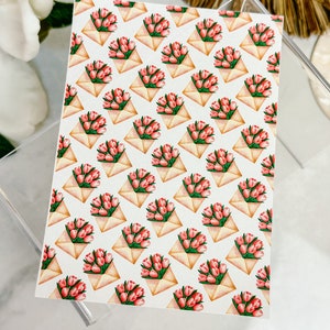 May include: A white card with a repeating pattern of pink flower bouquets in brown envelopes. The bouquets are arranged in a diagonal pattern.
