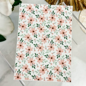 May include: A sheet of pink and green floral patterned paper. The pattern features a repeating design of pink flowers with green leaves on a white background.
