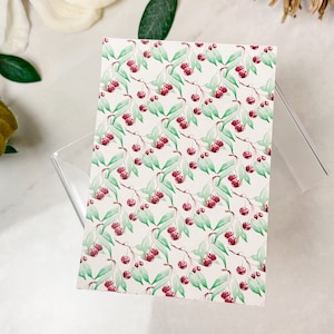 Peut inclure: Une carte blanche avec un motif répété de cerises rouges et de feuilles vertes. Les cerises sont peintes dans un style aquarelle.