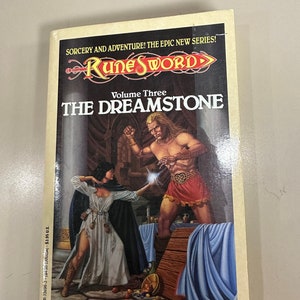 Peut inclure: Une couverture de roman fantastique représentant une femme en robe blanche et un homme en short rouge, tous deux tenant des orbes lumineux. Le titre du livre est "The Dreamstone" et il s'agit du tome trois de la série "Rune Sword".
