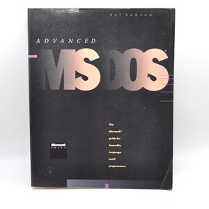 Op de afbeelding: Een zwart boek getiteld Advanced MS-DOS door Ray Duncan, uitgegeven door Microsoft Press. De kaft bevat grote, verloopkleurige tekst met MS-DOS, en kleinere gele tekst met The Microsoft guide for Assembly Language and C programmers.