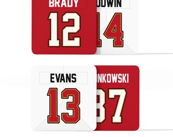 May include: Four white and red square jersey patches with the names Brady,  Godwin, Evans, and  Jinkowski and their corresponding numbers 12, 14, 13, and 37.