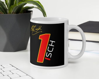 May include: White ceramic mug with a black background and a large red number one with a yellow outline. The number one has the word "ISCH" written vertically in white letters next to it. A signature is visible in the top left corner of the mug.