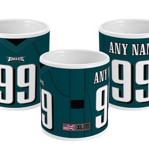 May include: Three white ceramic mugs with a green and black Philadelphia Eagles football jersey design. The mugs feature the team logo, the number 99, and the text "ANY NAME".