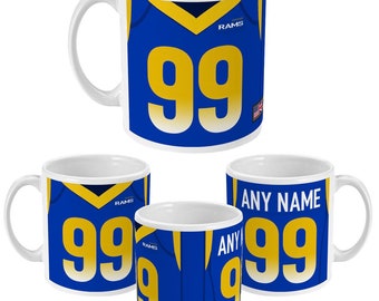Könnte beinhalten: Weiße Keramik-Kaffeetasse mit blauem und goldenem Design. Die Tasse zeigt ein Fußballtrikot mit der Nummer 99 und dem Wort "RAMS".