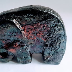 Könnte beinhalten: Eine kleine Elefanten-Skulptur aus Keramik mit schwarzer und roter Glasur. Der Elefant steht und hat seinen Rüssel nach unten gerollt.