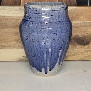May include: A blue and white ceramic vase with a textured glaze. The vase has a rounded body and a slightly flared opening.