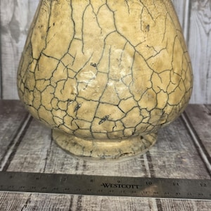 May include: A round, beige ceramic bowl with a dark, web-like crackle glaze pattern across its textured surface. The bowl sits behind a Westcott ruler, showing a width of approximately 5.5 inches at its widest point and a base diameter of 3 inches.