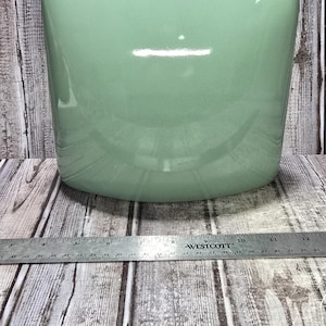 May include: A smooth, light mint green ceramic planter with a wide, rounded rectangular shape. A metal Westcott ruler is positioned in front of the planter, showing a width of approximately 10.5 inches across the base of the object.