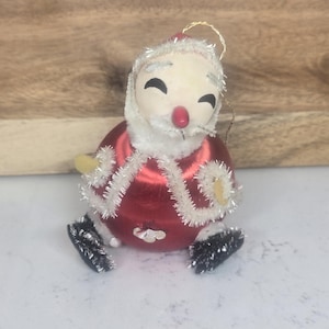 May include: Vintage Christmas ornament of Santa Claus. The ornament has a red body, white beard and trim, and black boots. The Santa Claus ornament is approximately 4 inches tall.