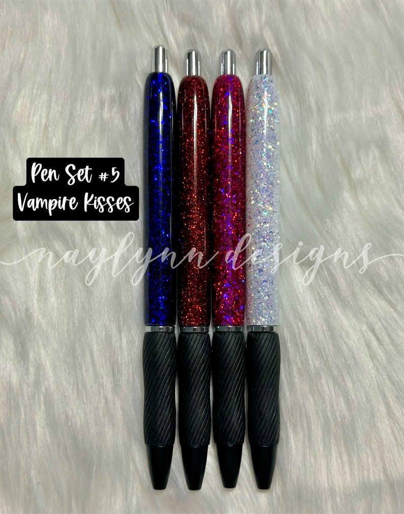 May include: Set of four pens with black barrels and glitter filled tops. The glitter colors are blue, red, pink, and white. The pens are labeled "Pen Set #5 Vampire Kisses".