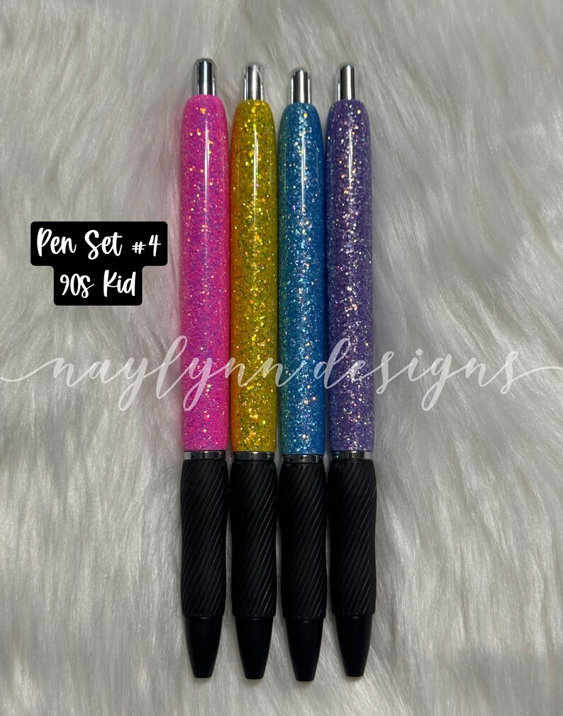 May include: Set of four glitter pens with black ink. The pens have a black rubber grip and a silver top. The glitter colors are pink, yellow, blue, and purple. The text "Pen Set #4 90s Kid" is visible in the image.