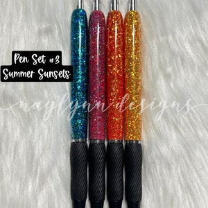 May include: Set of four glitter pens with black ink. The pens have a black grip and silver accents. The glitter colors are teal, pink, orange, and yellow. The text "Pen Set #3 Summer Sunsets" is visible in the image.