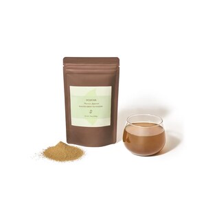 May include: A brown pouch of Hojicha roasted green tea powder with a light green label, a small pile of powder, and a glass of tea. The glass is filled with a brown liquid, and the pouch has text on it.