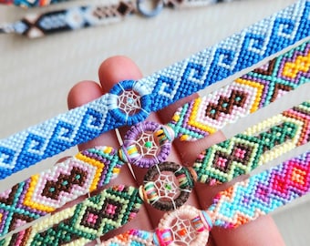 May include: A collection of colorful handmade friendship bracelets. Each bracelet features intricate woven patterns in various colors, including blue, green, pink, and yellow. Some bracelets incorporate small dreamcatcher charms.
