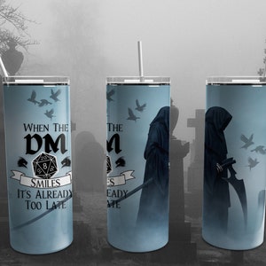May include: A tall, light blue tumbler with a white straw, featuring a design with a grim reaper, flying birds, and the text "WHEN THE DM SMILES IT'S ALREADY TOO LATE." The tumbler is designed for Dungeons and Dragons enthusiasts.